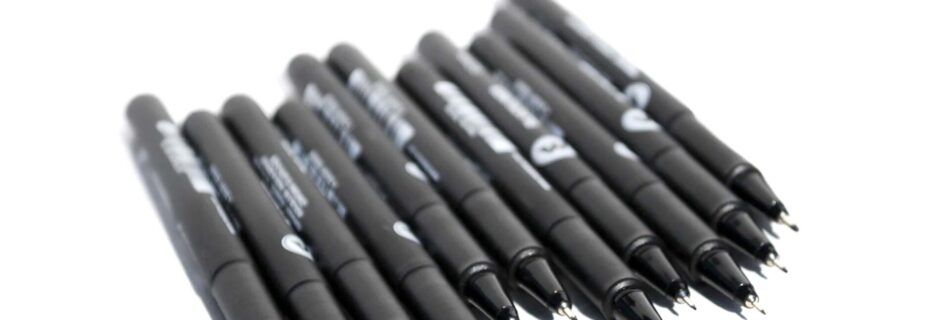 Eleven fineliners side by side, with the caps removed and marker tips in sight.