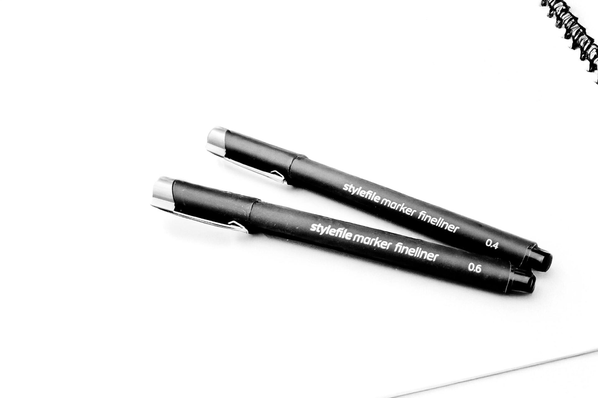 An edited photo of two black markers on white paper.